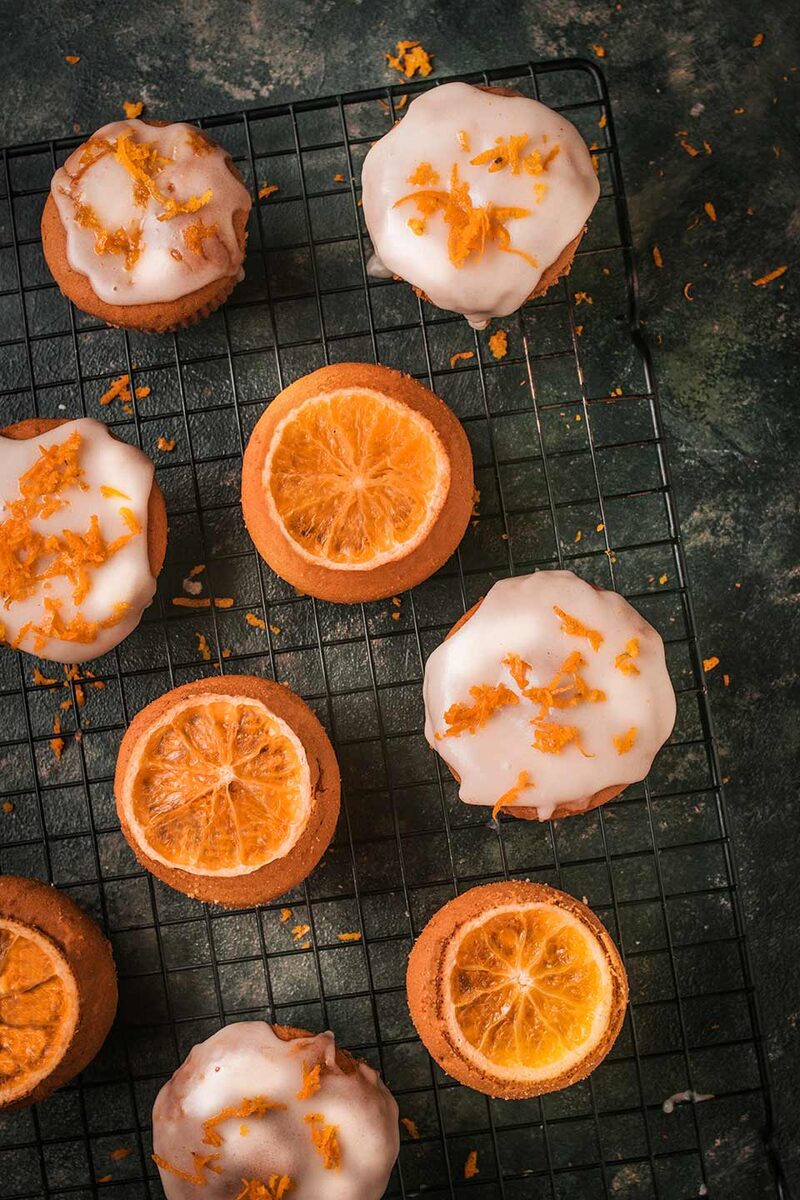 Glazed orange muffins with candied orange on a cooling rack